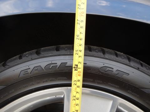 2003 Ford Crown Victoria - Close-up of a Goodyear Eagle GT tire sidewall and silver wheel with a tape measure held across it.