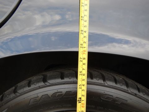 2003 Ford Crown Victoria - yellow tape measure runs vertically past a Goodyear Eagle GT tire and the dark fender above it.