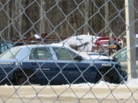 1991 Ford LTD Crown Victoria - A damaged police car sits in a snowy lot, its front end broken and rear wheels removed.