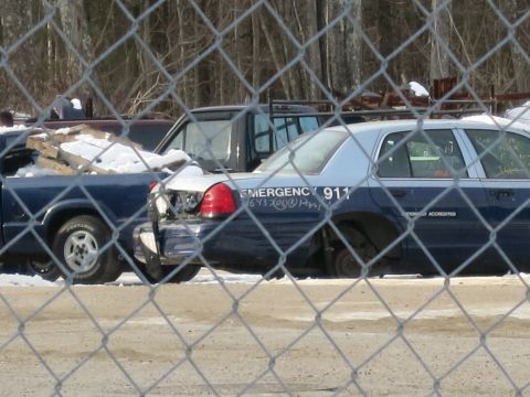 1991 Ford LTD Crown Victoria - Abandoned 1991 Ford Crown Victoria LTD police car in a junkyard, showing rear damage and missing parts.