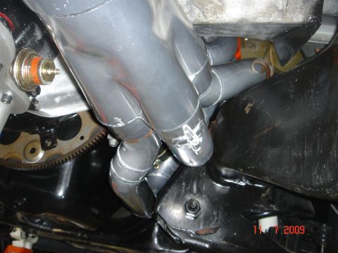 1990 Chevrolet Silverado 1500 - Close-up view of engine components, including exhaust pipes and a flywheel, with a visible date stamp.