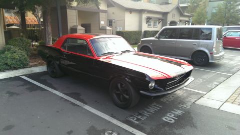 1987 Ford Bronco - A two-tone black and red coupe is parked in a lot next to other vehicles.