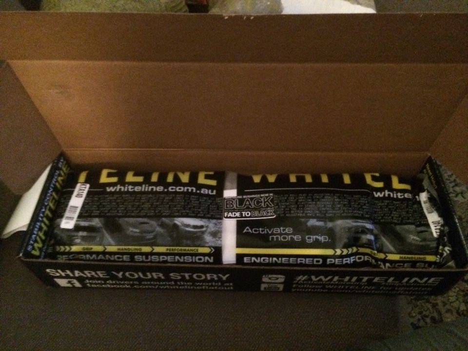 Whiteline performance suspension parts in an open cardboard box. Text includes 'whiteline.com.au' and 'Activate more grip.'