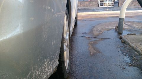 2012 Mazda Mazda 5 - Side view of a car's rear quarter panel and wheel on wet pavement.