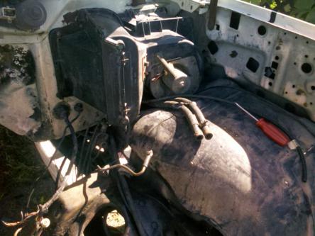 1982 Ford Bronco - The engine bay of a vehicle is shown with various components and a red-handled screwdriver.