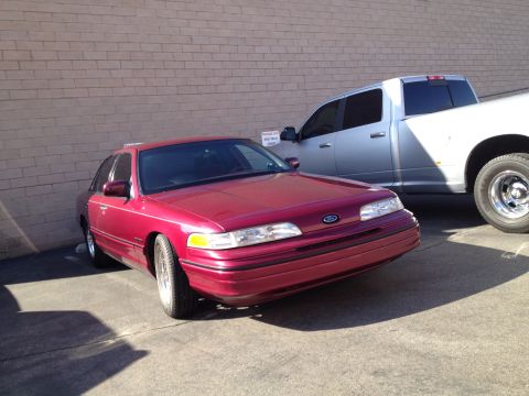 1992 Ford Crown Victoria - A red 1992 Ford Crown Victoria sedan is parked next to a silver pickup truck.