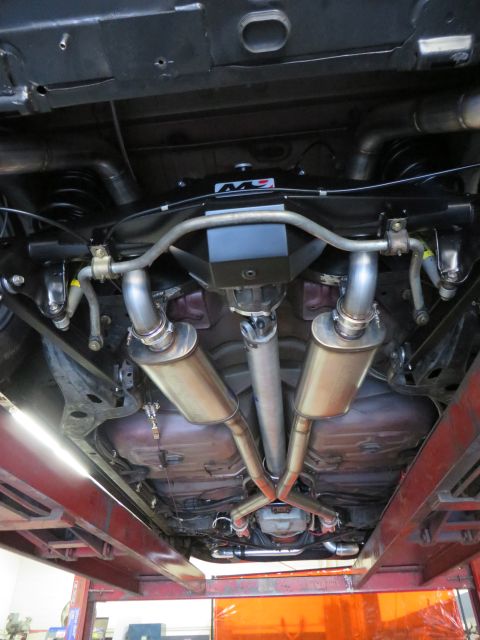 1992 Ford Crown Victoria - The undercarriage of a vehicle is visible, highlighting its dual exhaust system and suspension components.