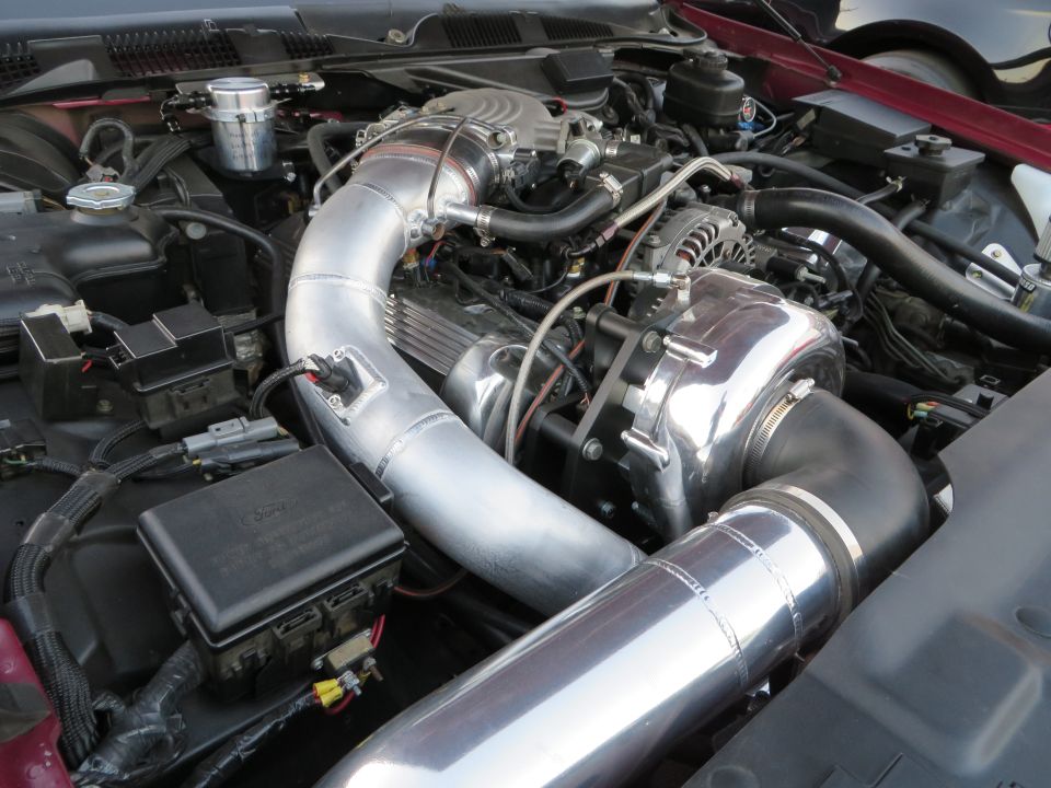 Engine bay with polished supercharger, intake piping, and fuse box
