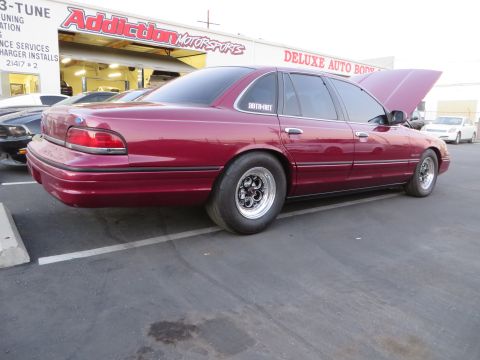 1992 Ford Crown Victoria - This maroon 1992 Ford Crown Victoria is parked outside a repair shop with its hood open.