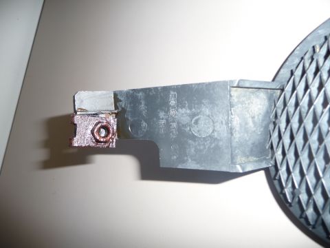 1993 Mazda MX-3 - A close-up view of a metal bracket and a textured plastic part, showing signs of wear and rust.