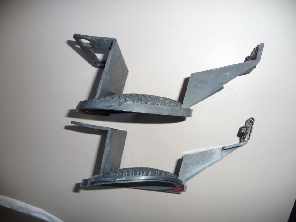 Two gray plastic car parts with textured surfaces and metal clips, viewed from above