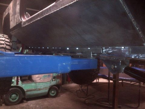 1985 Jeep CJ7 - A vehicle's undercarriage is supported by blue beams, with a forklift visible below.