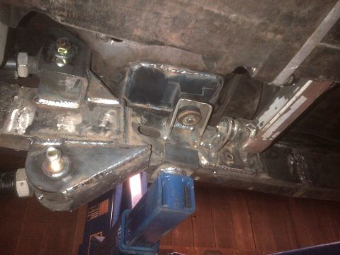 1985 Jeep CJ7 - Custom suspension modifications are visible on the undercarriage of a vehicle supported by a jack.