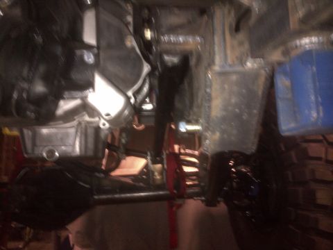 1985 Jeep CJ7 - The photo shows the undercarriage of a vehicle, focusing on the transmission and suspension parts.