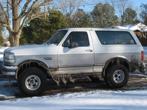 1994 Ford Bronco - A silver 1994 Ford Bronco is seen from the side, covered in snow and ice with icicles hanging from its wheel wells.