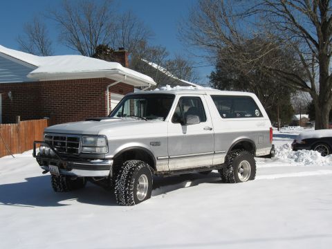 1994 Ford Bronco - Two-tone 1994 Ford Bronco with aftermarket bumper and large tires sits in the snow.