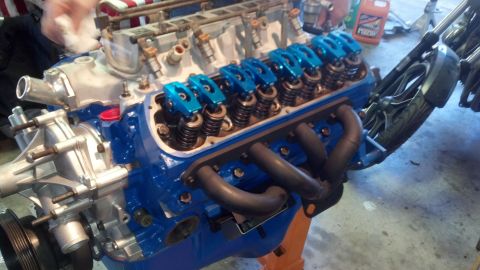 1988 Ford Bronco - Close-up of a V8 engine undergoing a rebuild, bright blue valve covers and black headers.
