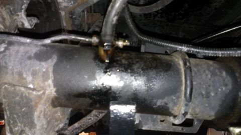 1996 Ford Bronco - A close-up view of a vehicle's undercarriage reveals a brake line with a visible leak and fluid residue.