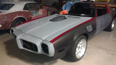 1972 Pontiac Trans Am - Two classic Pontiacs in a garage, one in primer and the other in a state of disrepair.