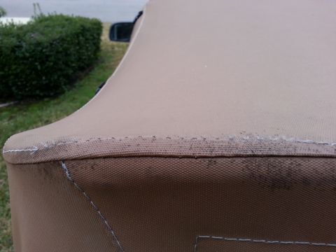 1992 Ford Bronco - Close-up view of the stitching on a tan soft top cover, with a portion of a vehicle visible in the background.