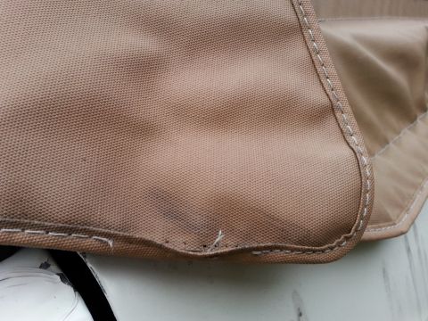 1992 Ford Bronco - Close-up of tan fabric with stitching, likely a soft top cover, with a Supermotors logo.