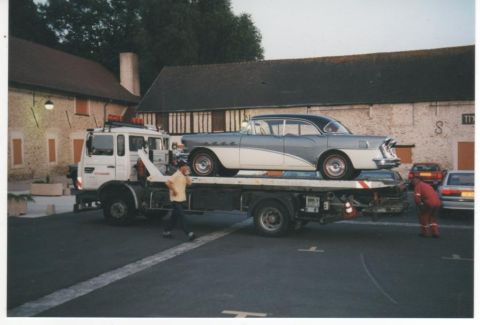 1991 Ford Crown Victoria - A classic two-tone Buick Century is loaded onto a tow truck, with workers attending to the vehicle.
