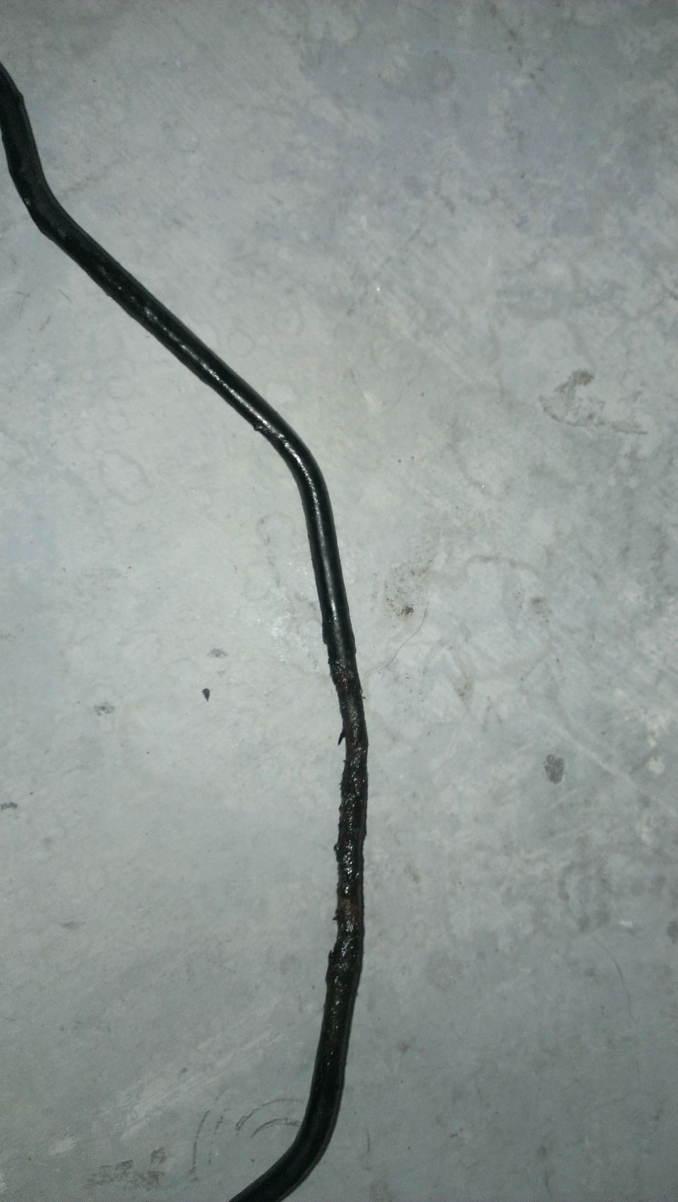 Damaged black brake line on concrete surface