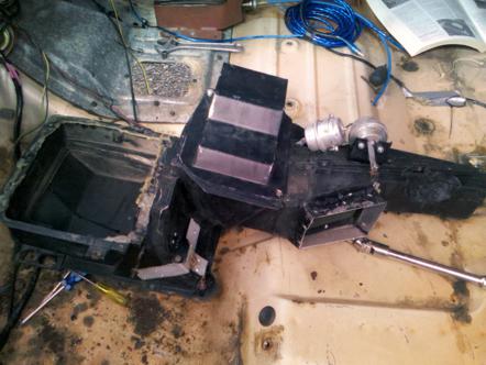 1982 Ford Bronco - Close-up of a vehicle's heater core assembly, showing ducting and a vacuum actuator, with tools nearby.