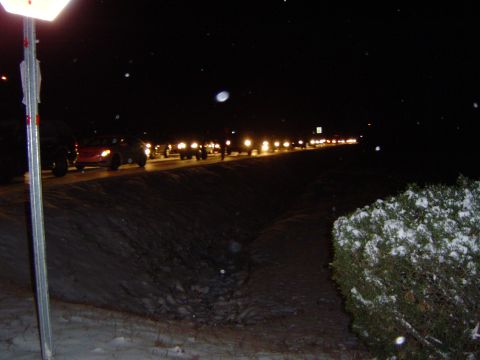 1986 Ford Bronco - A long line of vehicles are stopped on a road covered in snow during the nighttime.