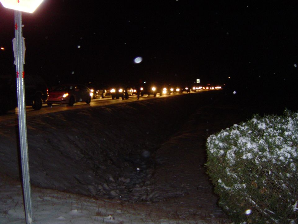 Cars in a line on a snowy road at night
