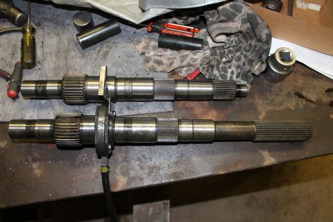 1995 Ford Bronco - Two transfer case output shafts are laid out on a workbench, possibly for comparison or repair.