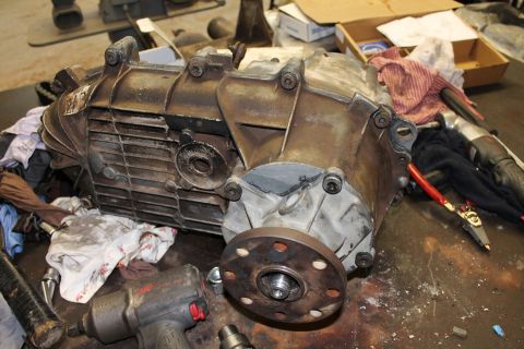 1995 Ford Bronco - A transfer case assembly sits on a workbench, surrounded by tools and shop rags.