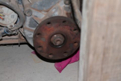 1995 Ford Bronco - Close-up of a rusty transfer case flange, part of a vehicle's drivetrain, with visible bolt holes and housing.