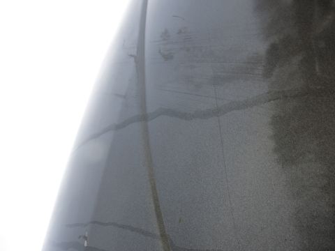 1991 Ford LTD Crown Victoria - Close-up of a gray vehicle fender showing damage and water marks.