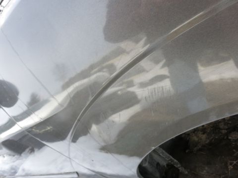 1991 Ford LTD Crown Victoria - Close-up of a silver car fender showing scratches and reflections.