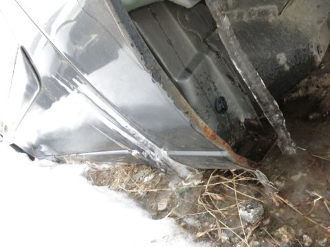 1991 Ford LTD Crown Victoria - The undercarriage of a vehicle shows significant rust and ice accumulation along the rocker panel.