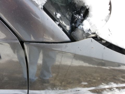 1991 Ford LTD Crown Victoria - A close-up view of a car's fender and the lower part of the windshield, partially covered in snow.