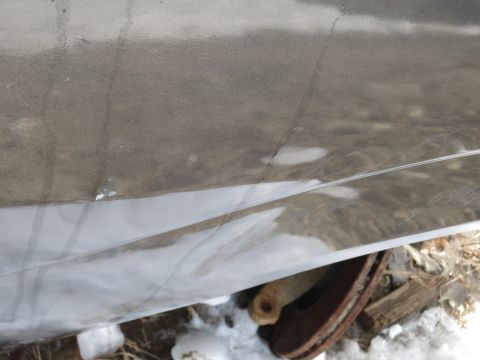 1991 Ford LTD Crown Victoria - Close-up of a vehicle's side panel, showing damage and a rusty wheel.