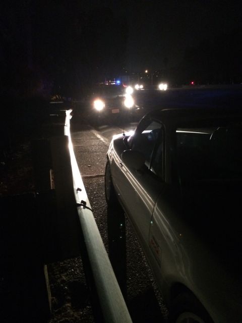 1991 Mazda Miata - A white convertible sports car is parked on the side of the road at night, with other vehicles visible in the distance.