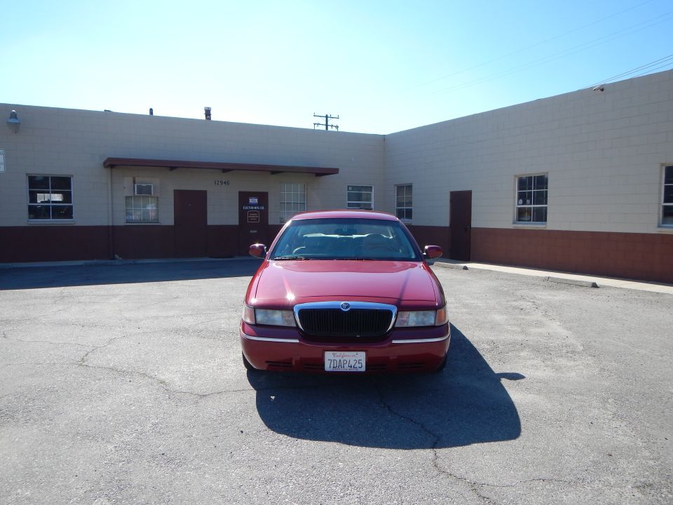Red 2002 Mercury Grand Marquis parked outside a commercial building