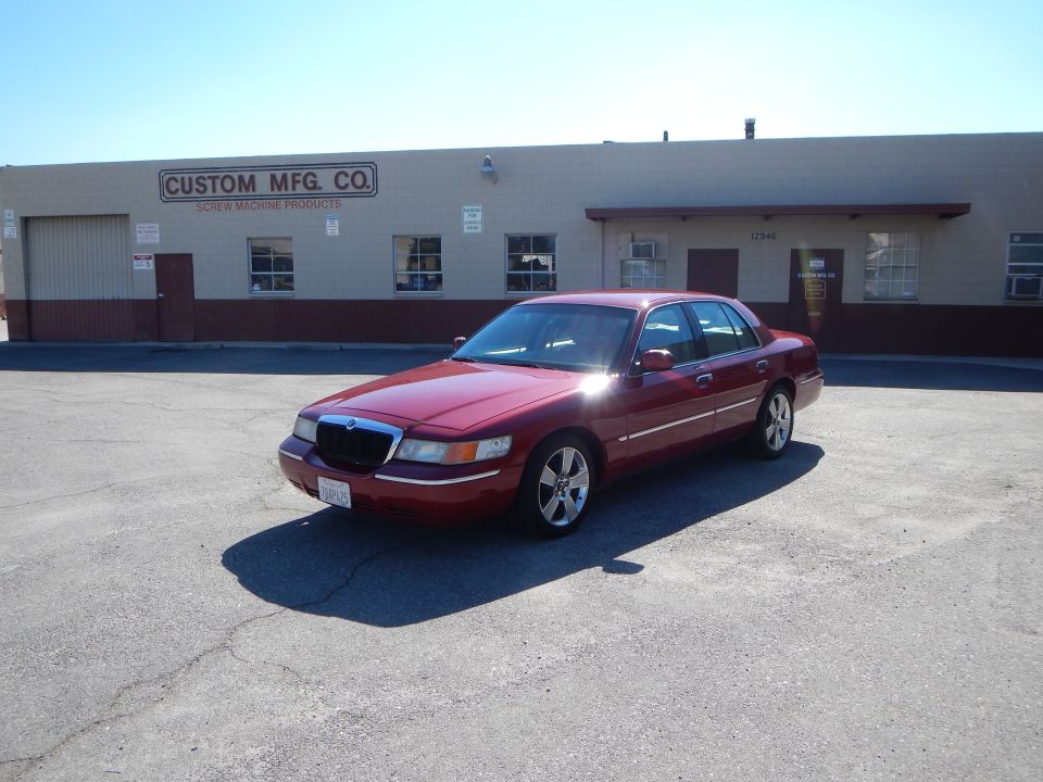 Red 2002 Mercury Grand Marquis parked in front of a commercial building