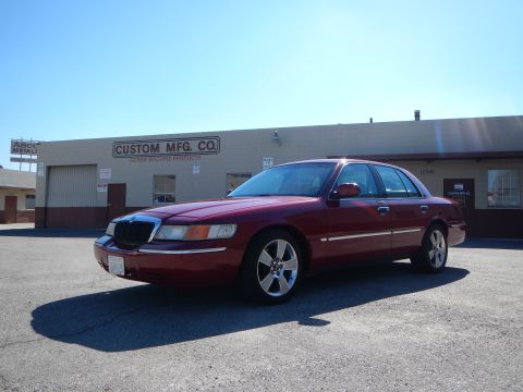 2002 Mercury Grand Marquis - Red 2002 Mercury Grand Marquis parked in front of a commercial building with "Custom Mfg. Co." signage.