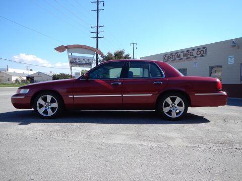 2002 Mercury Grand Marquis - Side profile of a red 2002 Mercury Grand Marquis parked in front of a commercial building.