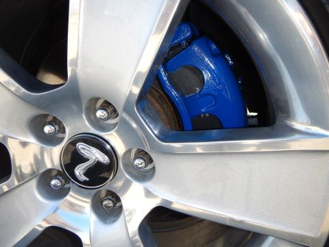 2002 Mercury Grand Marquis - Close-up of a silver alloy wheel with a bright blue brake caliper visible through the spokes.