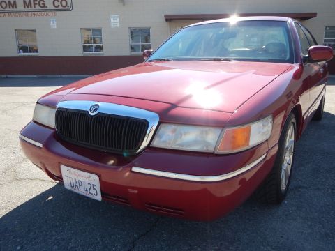2002 Mercury Grand Marquis - This red 2002 Mercury Grand Marquis is shown from a 3/4 front angle, highlighting its chrome grille and aftermarket wheels.