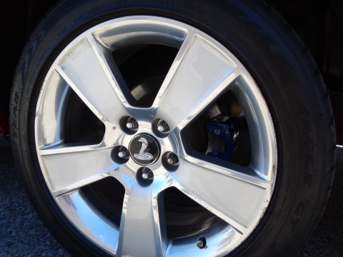 2002 Mercury Grand Marquis - Wheel with cobra logo and blue brake caliper. The tire has text that is not readable.