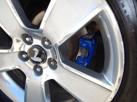 2002 Mercury Grand Marquis - A close-up shot of a car's wheel, a bright blue painted brake caliper and a distinctive cobra emblem on the hub.