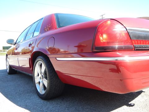 2002 Mercury Grand Marquis - Rear three-quarter view of a red 2002 Mercury Grand Marquis, chrome accents and distinctive wheels.