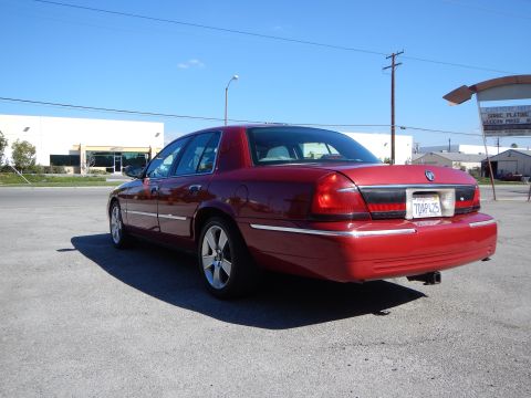2002 Mercury Grand Marquis - Red 2002 Mercury Grand Marquis with aftermarket wheels and a trailer hitch parked outside.