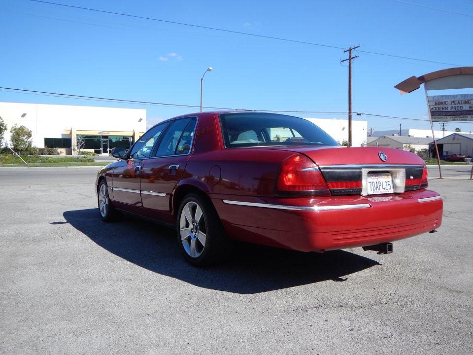 2002 Mercury Grand Marquis, rear 3/4 view, red paint, aftermarket wheels, trailer hitch